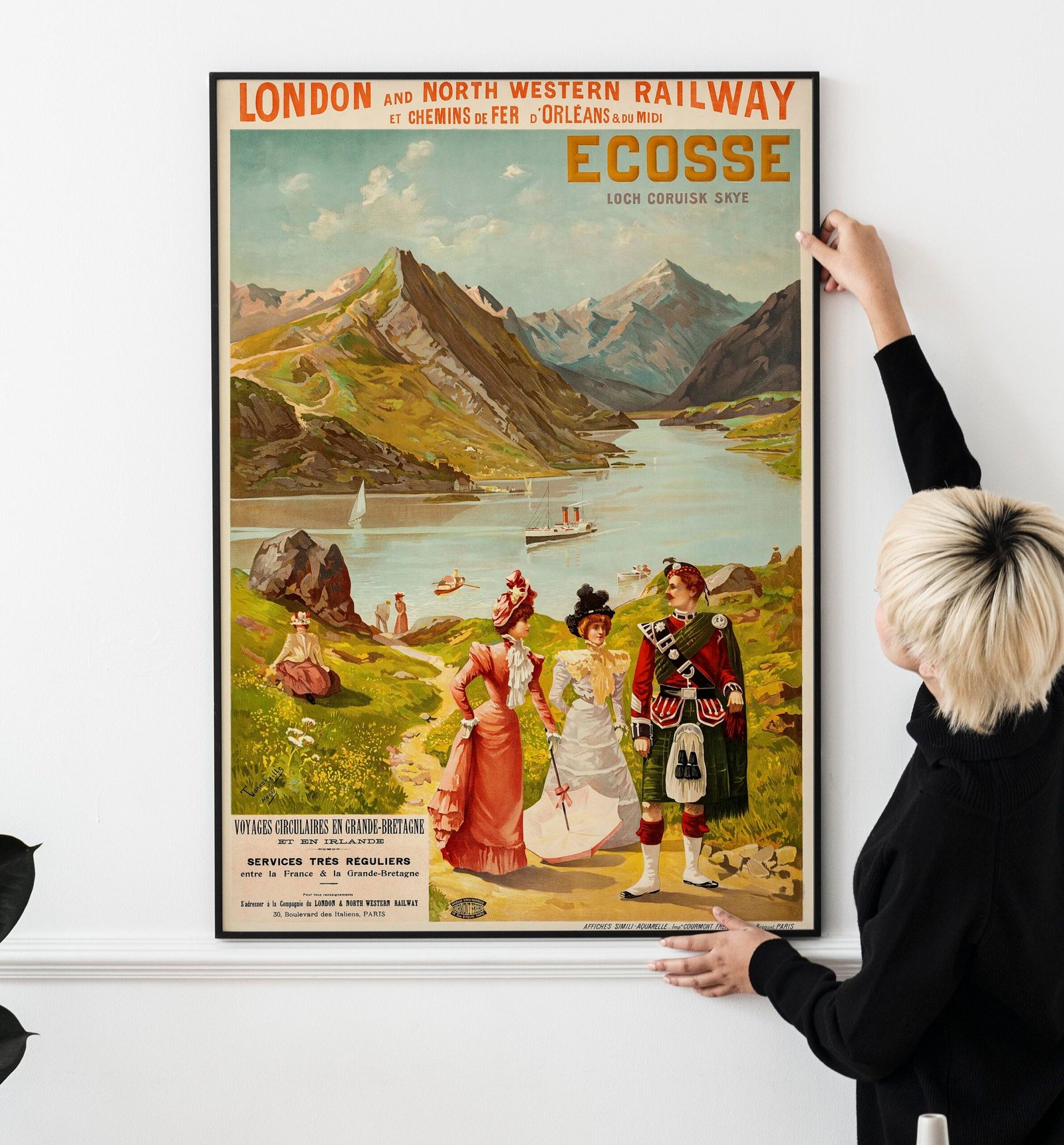 Blond haired Asian woman hanging a frame mockup on a white wall